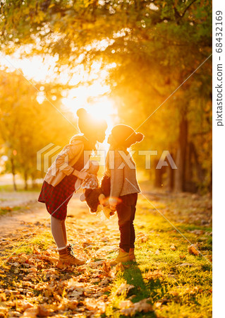sun rays. sisters with toys walk in autumn Park sun rays. sisters with toys walk in autumn Park 68432169