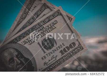 Girl holding money bill of 300 dollars on background of sea ocean Girl holding money bill of 300 dollars on background of sea ocean 68432572