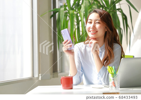 一個擁有智能手機和溫柔微笑的女人 68433493
