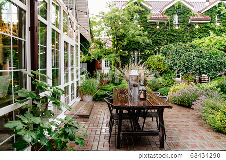 flowers and candles on table in yard in rain. flowers and candles on table in yard in rain. 68434290