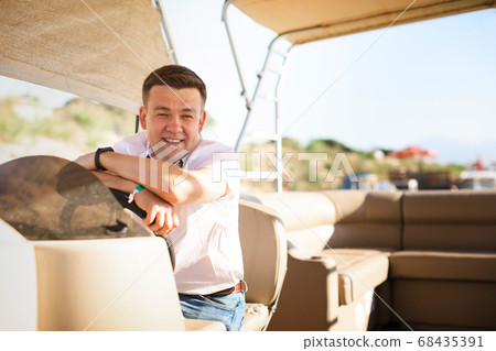man helm boat on pier. tours on water 68435391