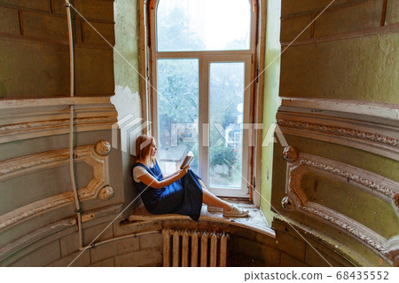 woman sits of window in old house and reads book woman sits of window in old house and reads book 68435552