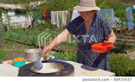 woman fry onions in tandir in garden. woman fry onions in tandir in garden. 68435637