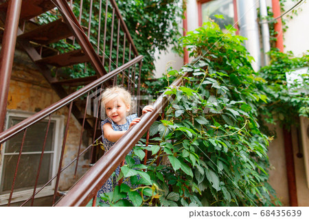 little girl stand in old yard with leafy stair. little girl stand in old yard with leafy stair. 68435639