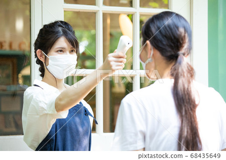 A female salesclerk who takes a temperature 68435649