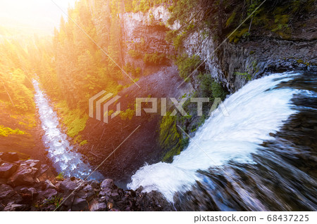 Beautiful View of a Waterfall rushing down in a rocky canyon Beautiful View of a Waterfall rushing down in a rocky canyon 68437225