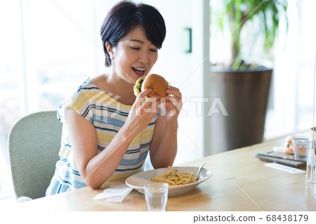 Middle woman eating hamburger 68438179