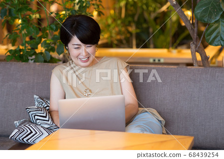 A middle-aged woman enjoying watching a computer 68439254