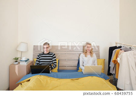 Couple with laptop sitting in bed Couple with laptop sitting in bed 68439755