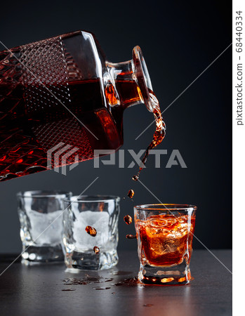 Whiskey pours into a frosted glass with natural Whiskey pours into a frosted glass with natural 68440334