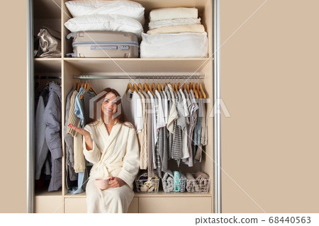 Well-organized wardrobe. Clothes storage. The girl sits in the closet and laughs. 68440563