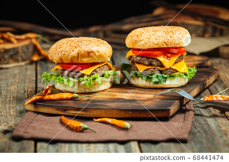 Two classic cheeseburgers on a wooden board 68441474
