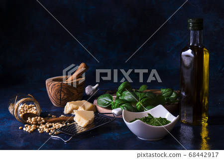 Ingredients to produce basil pesto, olive oil, pine nuts, basil, parmesan cheese with dark background 68442917