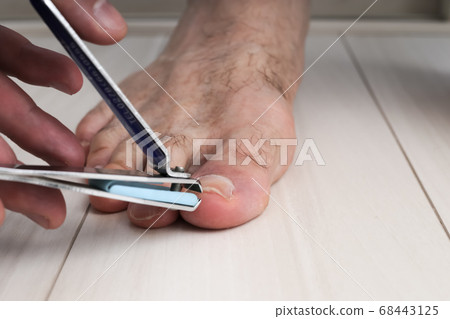 hands of a man who cuts his toenails with a nail hands of a man who cuts his toenails with a nail 68443125