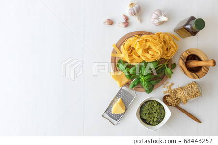 Ingredients to produce basil pesto, olive oil, pine nuts, basil, parmesan cheese with white background 68443252