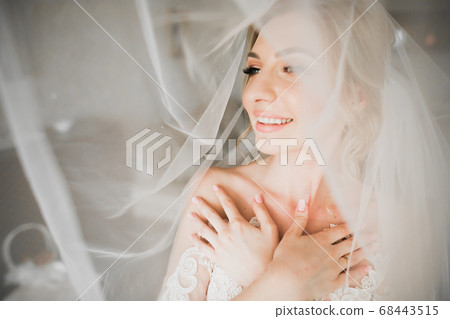 Luxury bride in white dress posing while preparing for the wedding ceremony 68443515