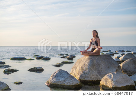 Young woman meditating near sea 68447017