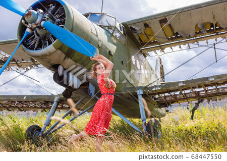 Young woman in a red pin up style dress stands by 68447550
