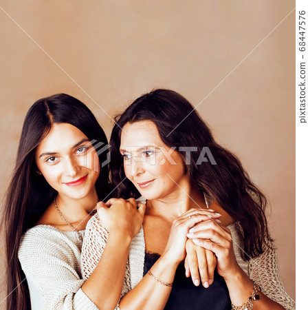 cute pretty teen daughter with mature mother hugging, fashion style brunette makeup together, warm colors cute pretty teen daughter with mature mother hugging, fashion style brunette makeup together, warm colors 68447576