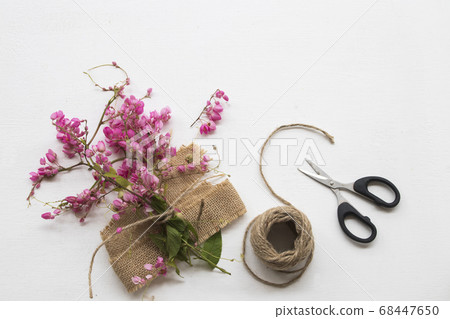 little pink flowers on sack ,scissors ,rope and decorate light arrangement flat lay style  68447650