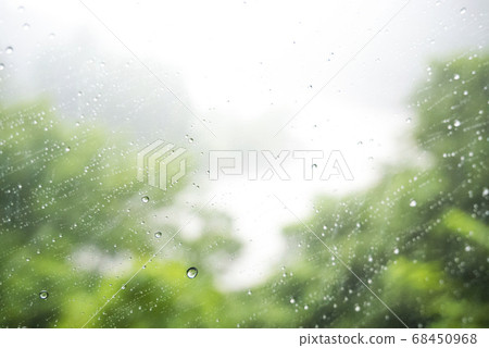 Window glass with raindrops and blurred trees through the window glass 68450968