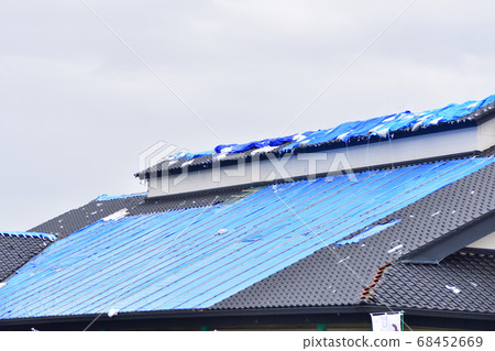 Blue tarpaulin stretched as an emergency measure on roofs damaged by strong winds 68452669