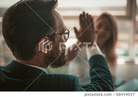 Positive project managers celebrate successful deal. Enthusiastic business people giving five each other in sign of good job and hands solidarity. American spirit concept. Close up shot. Tinted image 68454037