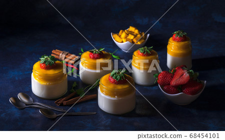 Panna cotta italian dessert with mango jelly with touch of red hot chili Piri-Piri, dark background 68454101