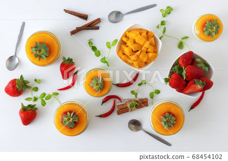 Panna cotta italian dessert with mango jelly with touch of red hot chili Piri-Piri, white background 68454102