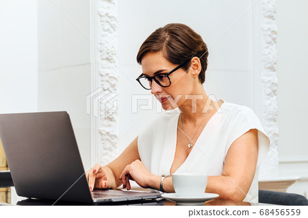 Caucasian woman typing on laptop while sitting at table 68456559