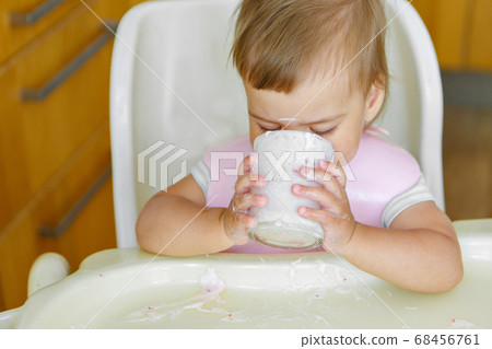 portrait of a child who drinks yogurt from a glass. smeared face with food portrait of a child who drinks yogurt from a glass. smeared face with food 68456761