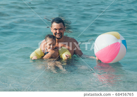 A young father and daughter swim in the sea. swimming training. ball game A young father and daughter swim in the sea. swimming training. ball game 68456765