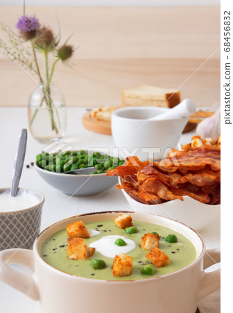 Homemade creamy grean pea soup with slices of grilled bacon and roasted rusks, white background. Homemade creamy grean pea soup with slices of grilled bacon and roasted rusks, white background. 68456832