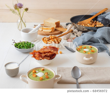 Homemade creamy grean pea soup with slices of grilled bacon and roasted rusks, white background. 68456972