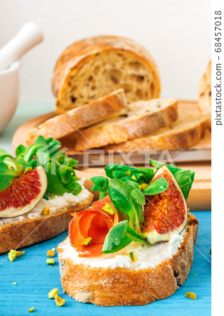 Fresh toats with feta cheese, bacon, fresh figs, green salad and crushed pistachio nuts. 68457018