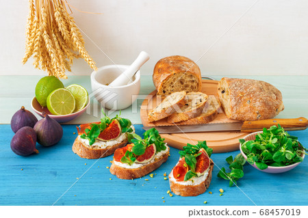 Fresh toats with feta cheese, bacon, fresh figs, green salad and crushed pistachio nuts. 68457019