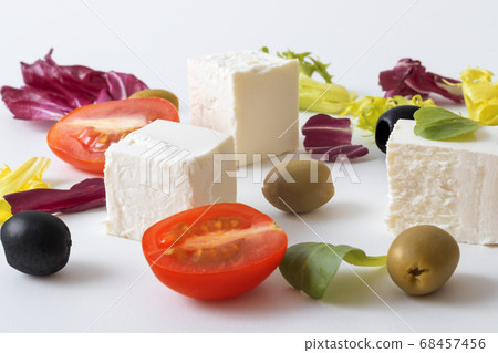 Variation of salads with Greek cheese , green and black olives, lettuce leaves, halfs of cherry tomato. White background. Variation of salads with Greek cheese , green and black olives, lettuce leaves, halfs of cherry tomato. White background. 68457456