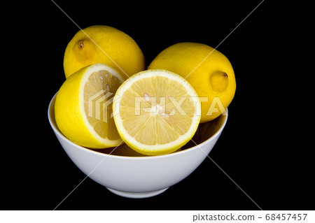 Whole and Cut Lemons in White Bowl on Black Whole and Cut Lemons in White Bowl on Black 68457457