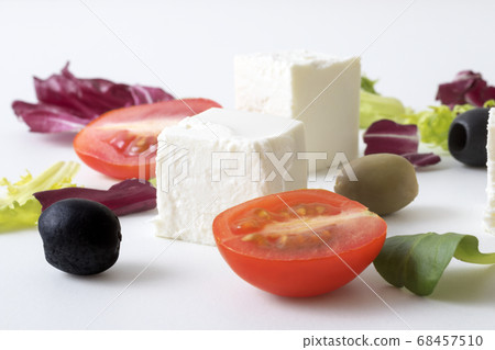 Variation of salads with Greek cheese , green and black olives, lettuce leaves, halfs of cherry tomato. White background. Variation of salads with Greek cheese , green and black olives, lettuce leaves, halfs of cherry tomato. White background. 68457510