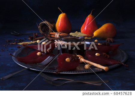 Poached pears with hibiscus syrup, sweet fruit dessert with hazelnuts and anise stars spice. White wooden table.  68457628