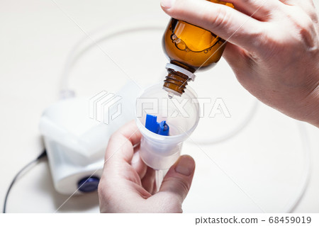 dripping solution from vial into nebulizer 68459019