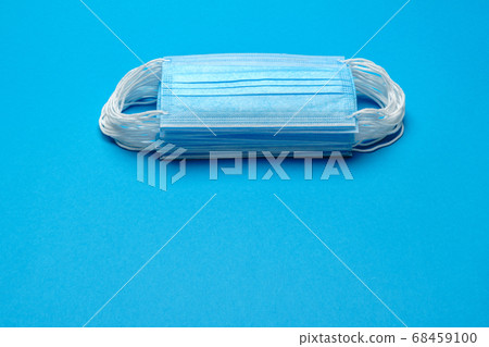 Stack of Disposable blue medical face masks on blue background Stack of Disposable blue medical face masks on blue background 68459100