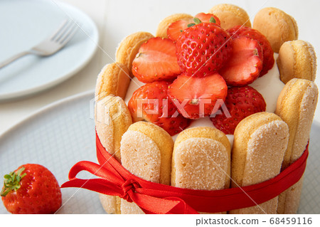 Charlotte, French strawberry dessert, tied up with a scarlet ribbon, cup of coffee, white background Charlotte, French strawberry dessert, tied up with a scarlet ribbon, cup of coffee, white background 68459116