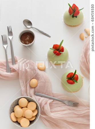 No-bake strawberry mini sphere matcha cheesecakes with bowl of salt caramel and biscuits 68459380