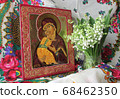 Traditional orthodox icon of the Mother of God. Icon Vladimirskaya. Handwritten icon of the Virgin Mary with Jesus Christ on the background of Ukrainian rushnyks and lilies of the valley. 68462350