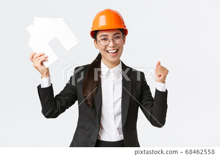 Successful winning asian female construction engineer, team lead architect achieve goal, holding house maket and fist pump in rejoice, celebrating victory in helmet and business suit Successful winning asian female construction engineer, team lead architect achieve goal, holding house maket and fist pump in rejoice, celebrating victory in helmet and business suit 68462558