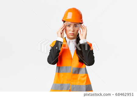 Serious-looking young asian female construction manager follow safety protocol, wearing protective glasses and helmet before entering enterprise, standing white background Serious-looking young asian female construction manager follow safety protocol, wearing protective glasses and helmet before entering enterprise, standing white background 68462951