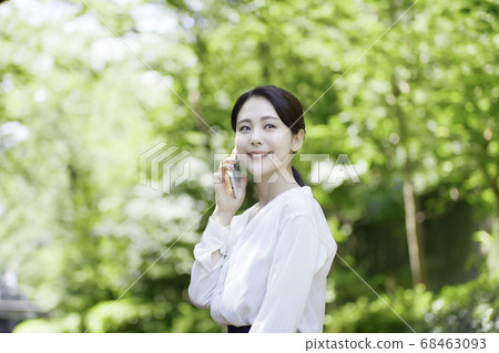 看智能手機的少婦反對新鮮的綠樹 看智能手機的少婦反對新鮮的綠樹 68463093