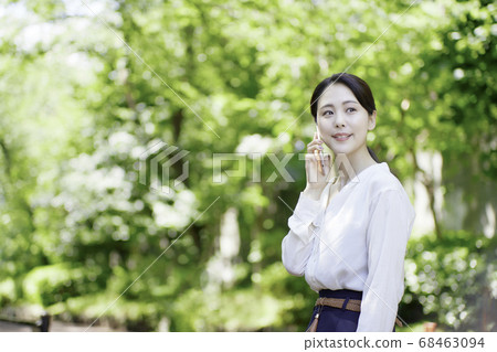 看智能手機的少婦反對新鮮的綠樹 看智能手機的少婦反對新鮮的綠樹 68463094