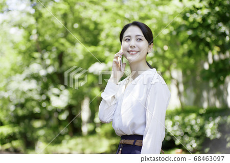 看智能手機的少婦反對新鮮的綠樹 看智能手機的少婦反對新鮮的綠樹 68463097